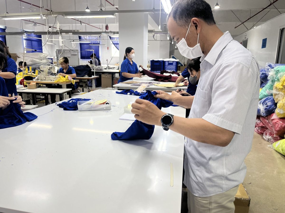 縫製責任者が縫い上がりを手に取って確認する様子|ベトナム自社縫製工場